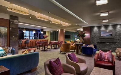 Lounge with colorful armchairs, bar seating, and warm lighting creating a relaxed social atmosphere