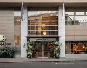 Street view of DoubleTree by Hilton entrance with large windows and floral decorations around doors