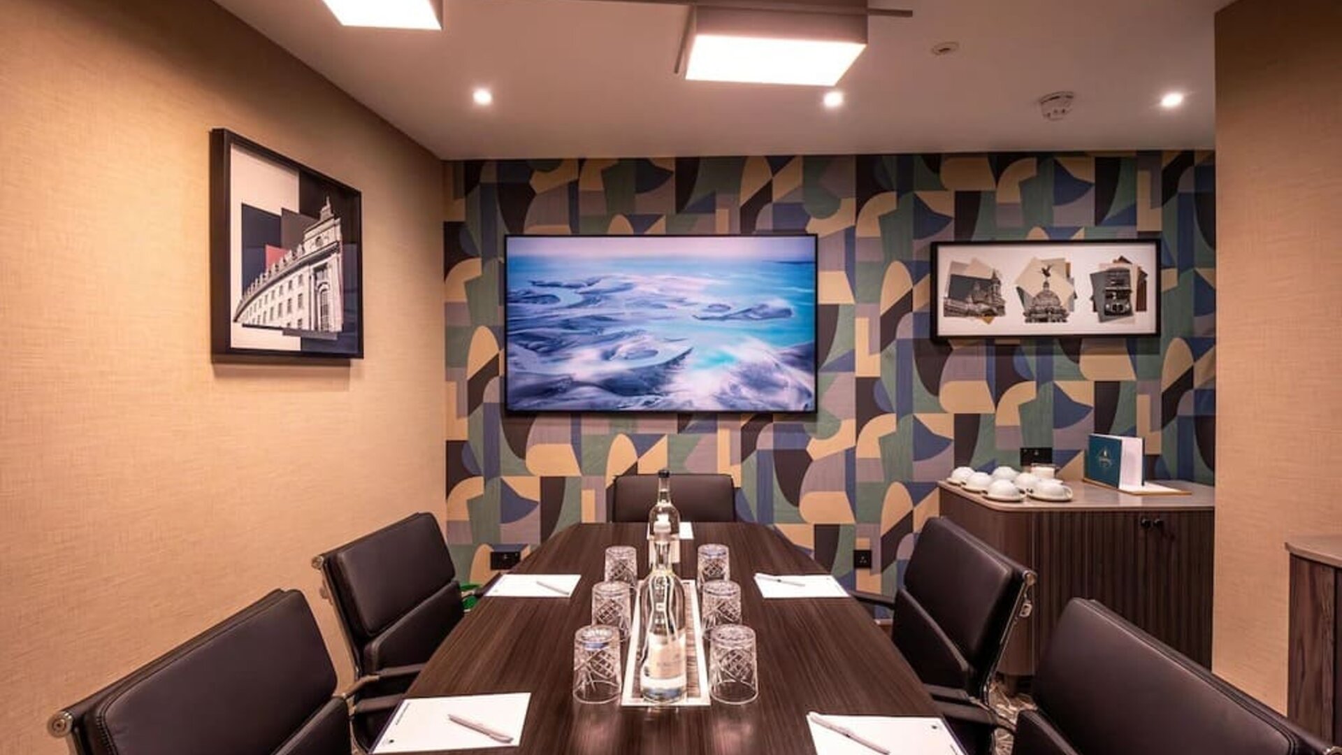 Private meeting room with long conference table, leather chairs, and wall-mounted television