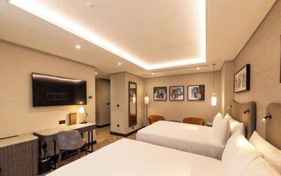 Contemporary room with two queen beds, wood flooring, framed artwork, and recessed ceiling lights