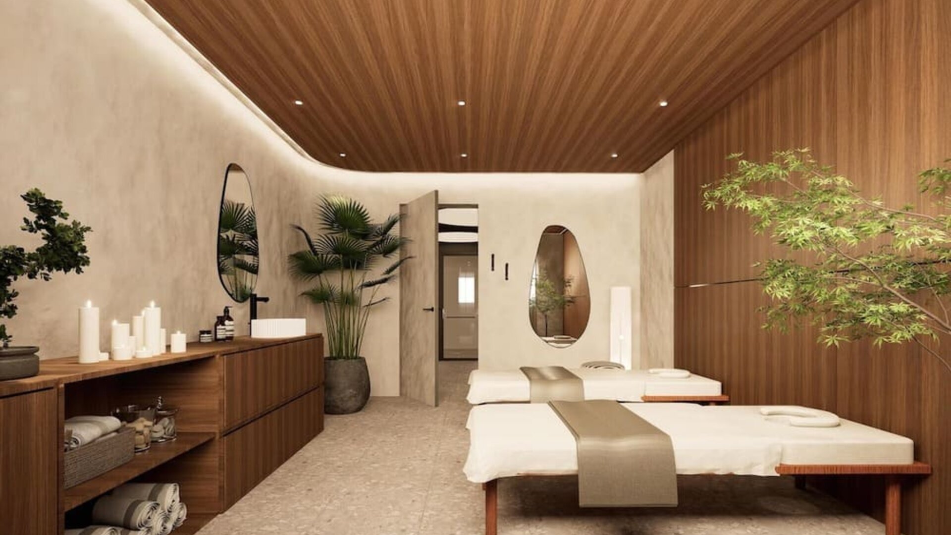 Spa treatment room with two massage tables, wood-paneled walls, candles, and indoor plants