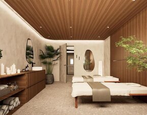 Spa treatment room with two massage tables, wood-paneled walls, candles, and indoor plants