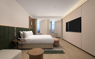 King bedroom with mountain and city views through corner windows, chaise lounge, and patterned bench