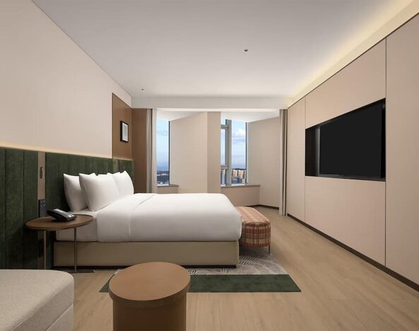King bedroom with mountain and city views through corner windows, chaise lounge, and patterned bench
