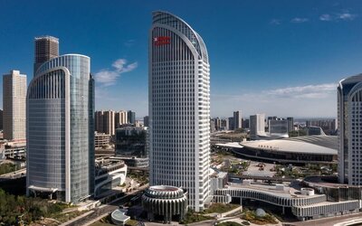 Curved glass high-rise towers beside a large convention center under a clear blue daytime sky