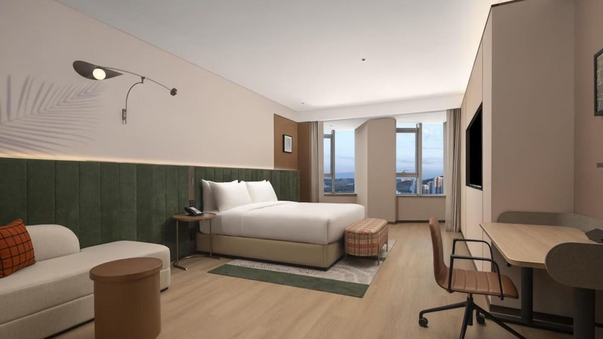 Spacious king room with green upholstered headboard, sofa seating, desk, and large city-view windows