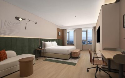 Spacious king room with green upholstered headboard, sofa seating, desk, and large city-view windows