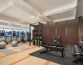 Fitness center with treadmills, free weights, workout bench, yoga mats, and floor-to-ceiling windows