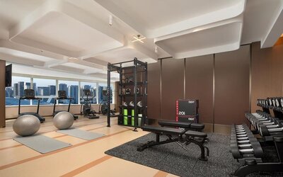 Fitness center with treadmills, free weights, workout bench, yoga mats, and floor-to-ceiling windows