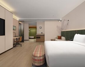 King guest room with plaid bench, workspace, cushioned seating area, and soft recessed lighting
