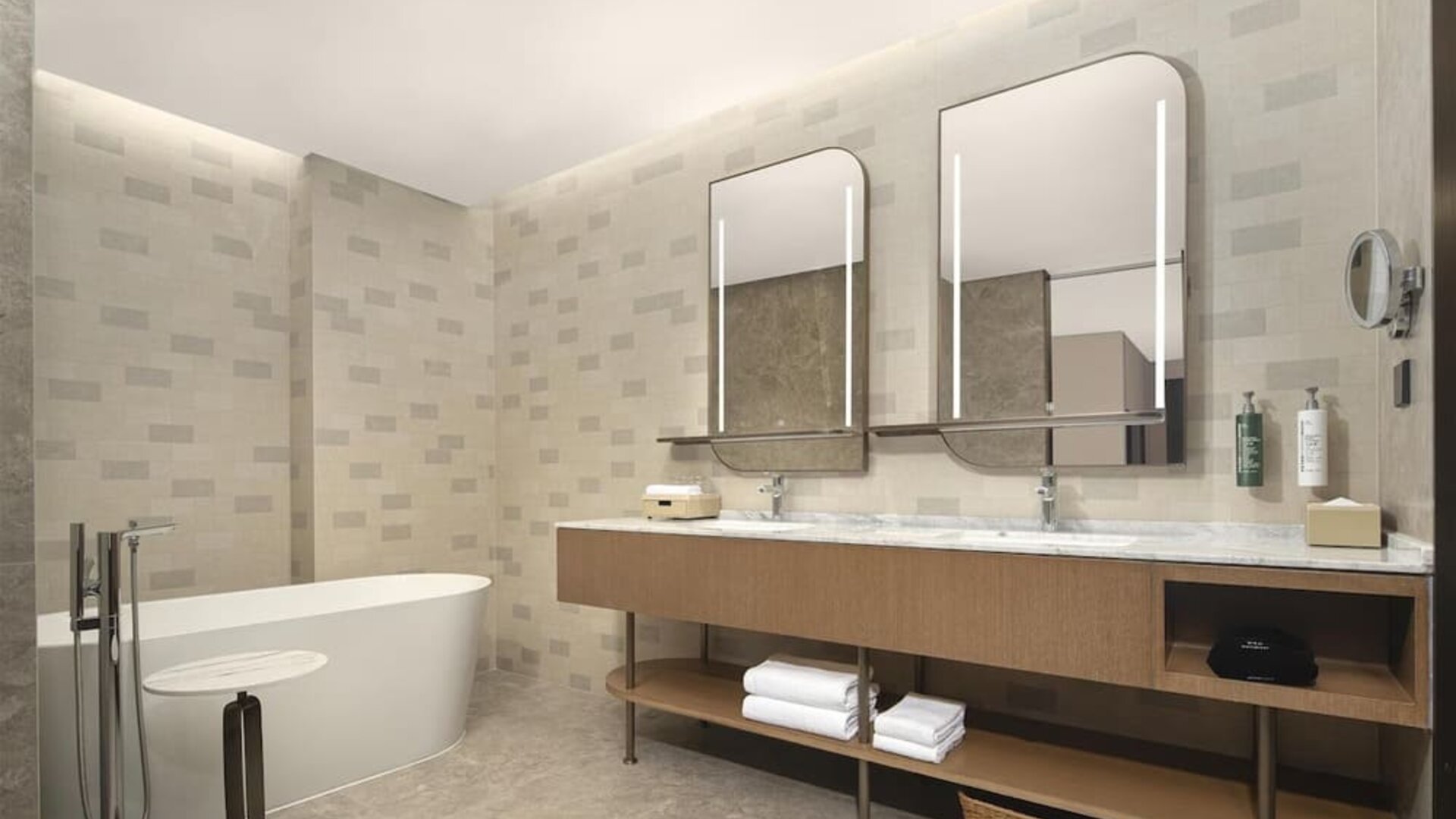 Spacious bathroom with freestanding bathtub, double illuminated mirrors, and long marble vanity