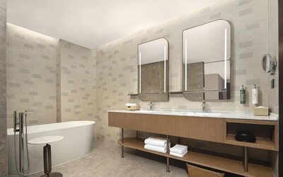 Spacious bathroom with freestanding bathtub, double illuminated mirrors, and long marble vanity