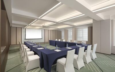 Conference room with U-shaped meeting setup, navy tablecloths, projector screen, and white chairs