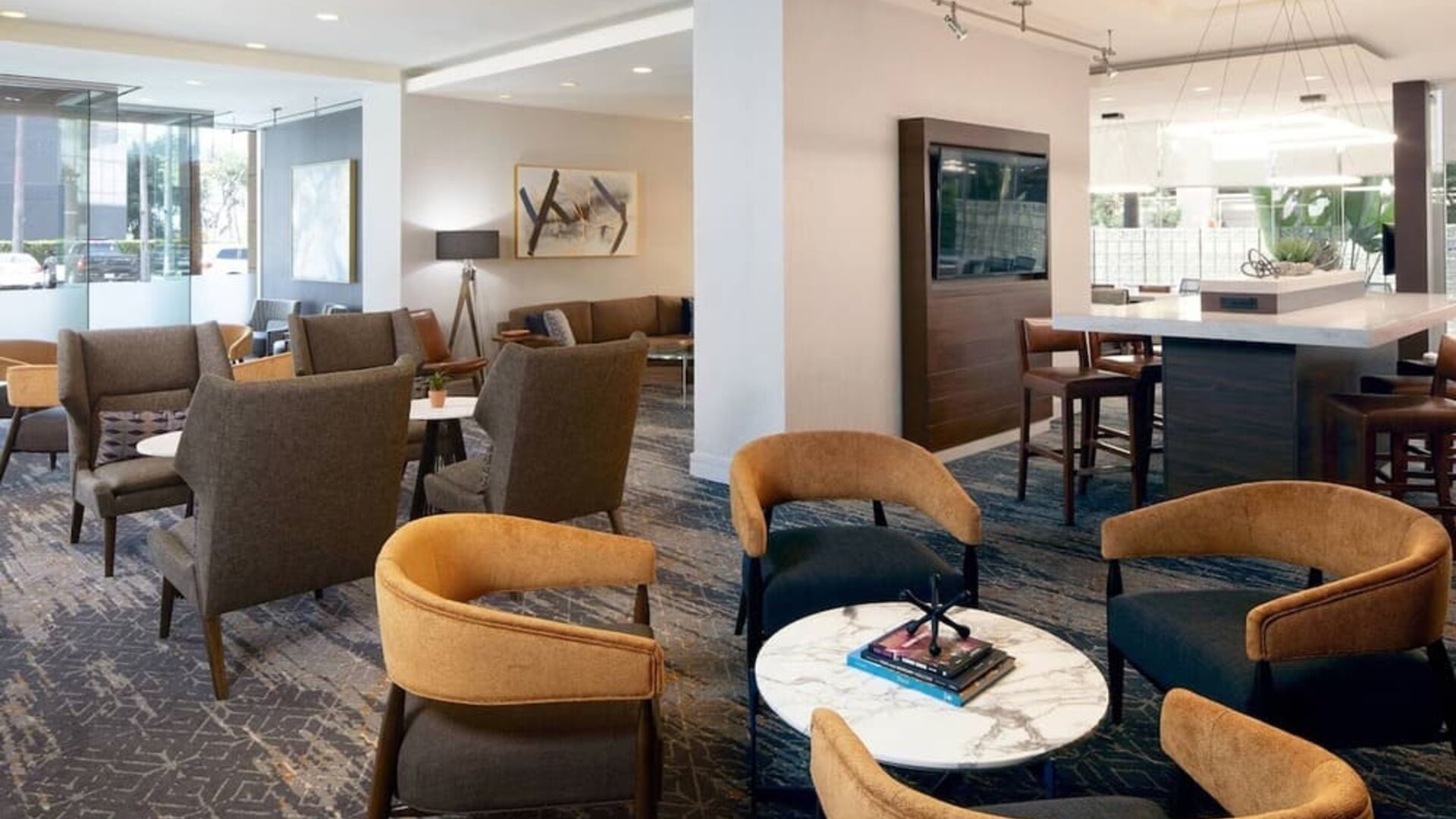 Lobby seating area with contemporary armchairs, marble tables, and warm neutral décor at Courtyard By Marriott Los Angeles LAX/Century Boulevard.