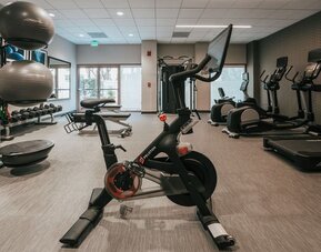 Modern hotel gym with Peloton bike, treadmills, elliptical machines, and weight station at Courtyard By Marriott Los Angeles LAX/Century Boulevard.