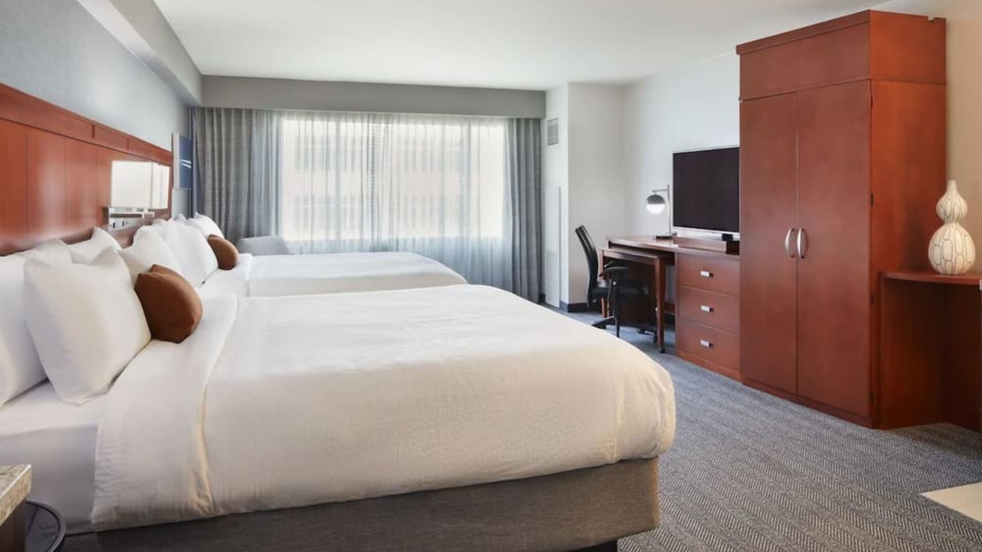 Guest room with two beds, workspace, wardrobe cabinet, and large window at Courtyard By Marriott Los Angeles LAX/Century Boulevard.