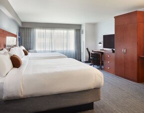 Guest room with two beds, workspace, wardrobe cabinet, and large window at Courtyard By Marriott Los Angeles LAX/Century Boulevard.