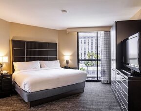 King guest room with floor-to-ceiling window, large TV cabinet, and contemporary furnishings at Embassy Suites By Hilton LAX Airport North.