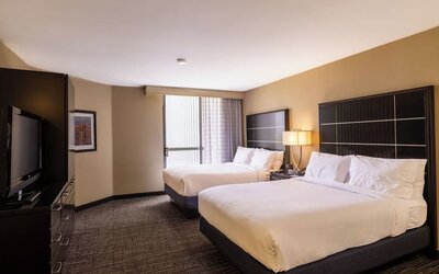 Double queen guest room with two beds, modern décor, and large window at Embassy Suites By Hilton LAX Airport North.