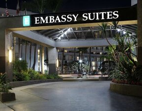 Nighttime front entrance with illuminated Embassy Suites signage and landscaped driveway at Embassy Suites By Hilton LAX Airport North.