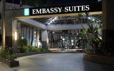 Nighttime front entrance with illuminated Embassy Suites signage and landscaped driveway at Embassy Suites By Hilton LAX Airport North.