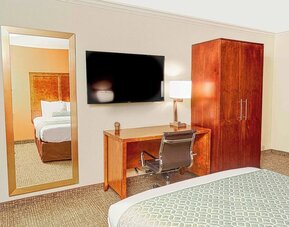 Guest room with mounted TV, wooden wardrobe, desk workspace, and full-length mirror at The Hills Inn Eagle Rock.