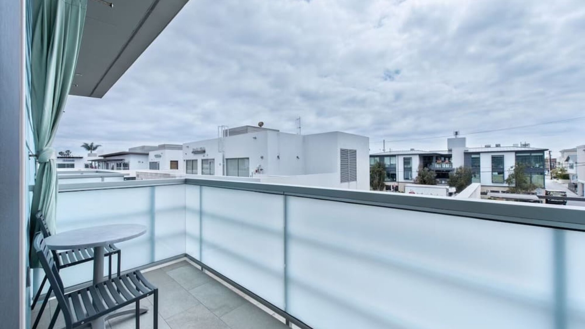 Private balcony with two chairs, small table, and neighborhood views at Shade Hotel Manhattan Beach.