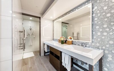 Modern bathroom with double vanity, illuminated mirror, walk-in shower, and patterned wall tiles at Shade Hotel Manhattan Beach.