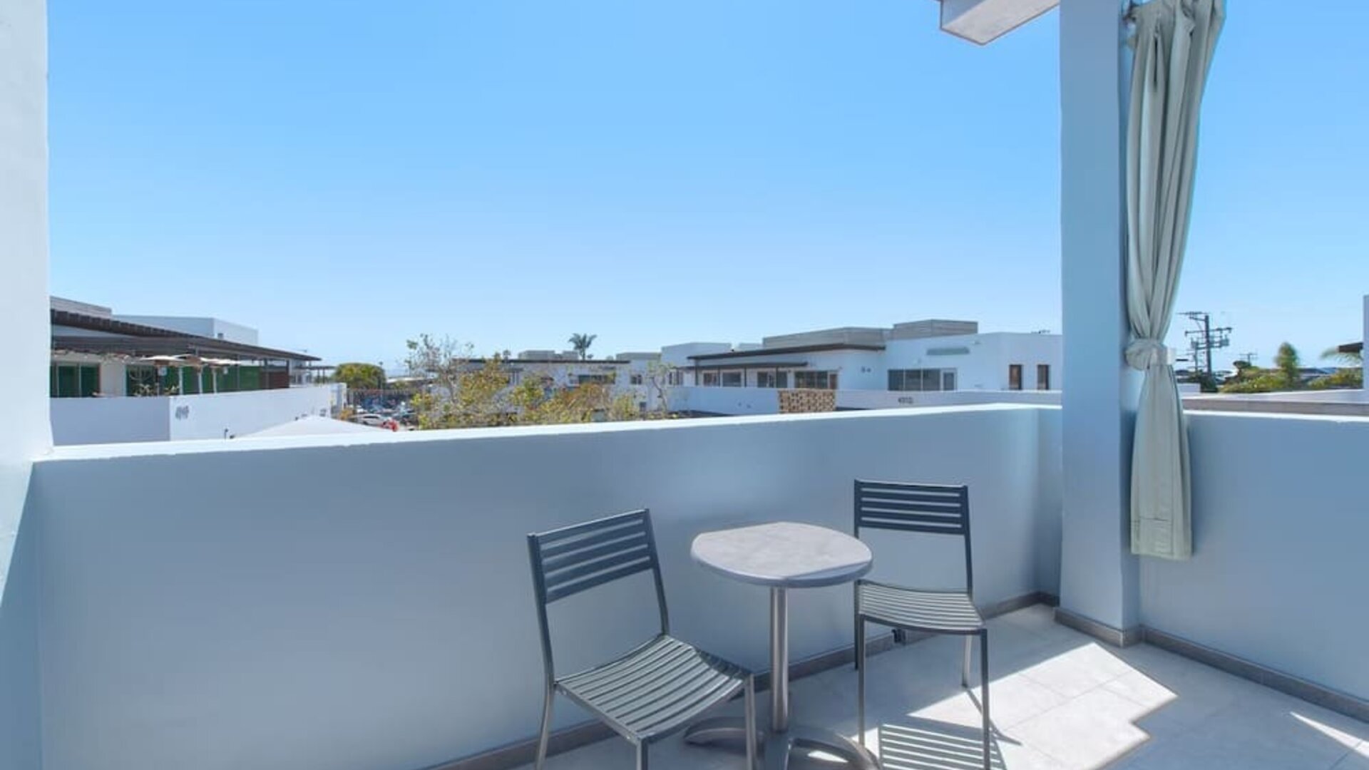 Balcony seating area with two chairs, round table, and residential neighborhood views at Shade Hotel Manhattan Beach.