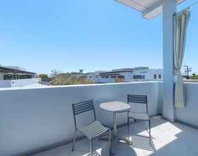 Balcony seating area with two chairs, round table, and residential neighborhood views at Shade Hotel Manhattan Beach.