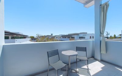 Balcony seating area with two chairs, round table, and residential neighborhood views at Shade Hotel Manhattan Beach.