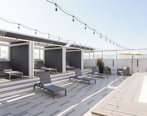Rooftop pool deck with shaded cabanas, lounge chairs, and string lighting at Shade Hotel Manhattan Beach.