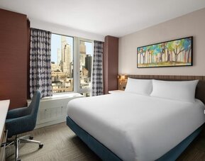 King bedroom with city views and workspace at Hilton Garden Inn New York/West 35th Street.