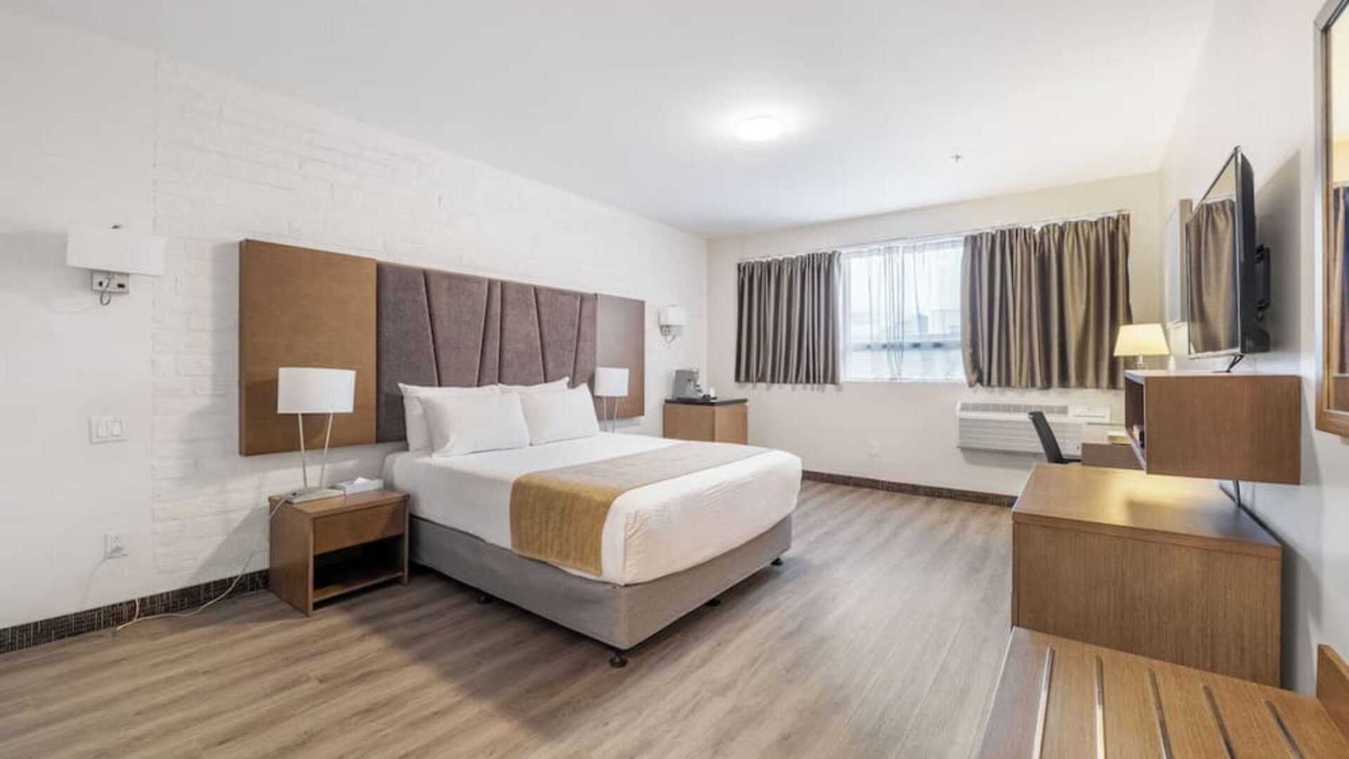 Large king guest room with modern décor and entertainment area at Hotel Montreal Metropolitan, An Ascend Collection Hotel.