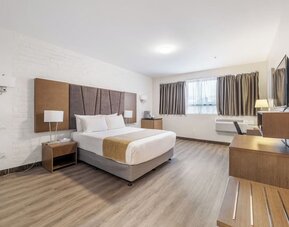 Large king guest room with modern décor and entertainment area at Hotel Montreal Metropolitan, An Ascend Collection Hotel.