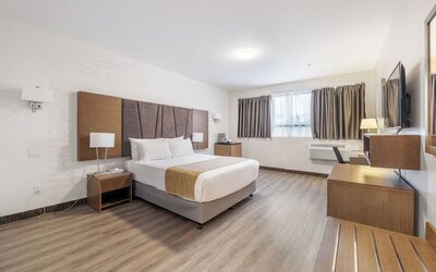 Large king guest room with modern décor and entertainment area at Hotel Montreal Metropolitan, An Ascend Collection Hotel.