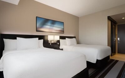 Guest room with two double beds and modern furnishings at Courtyard By Marriott New York JFK Airport.