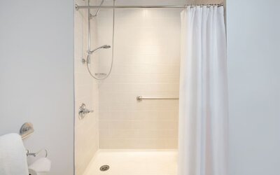 Accessible walk-in shower bathroom with safety handrails at Courtyard By Marriott New York JFK Airport.