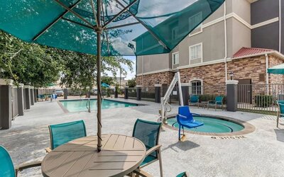 Outdoor swimming pool with accessible pool lift and shaded seating at La Quinta Inn & Suites By Wyndham Houston Energy Corridor.