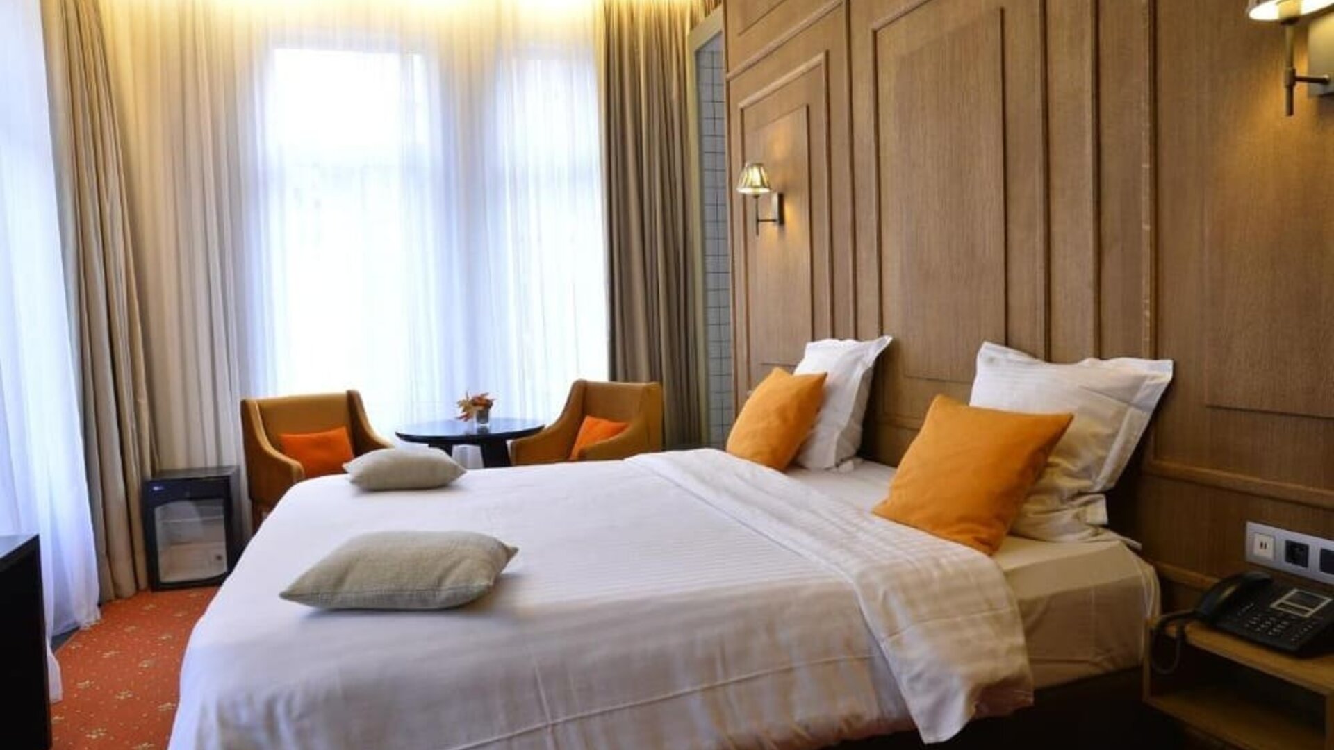 Spacious guest room with warm lighting, seating area, and contemporary furnishings at Hôtel Espérance.