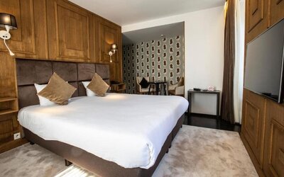 Spacious guest room with king bed, seating area, and television at Hôtel Espérance.