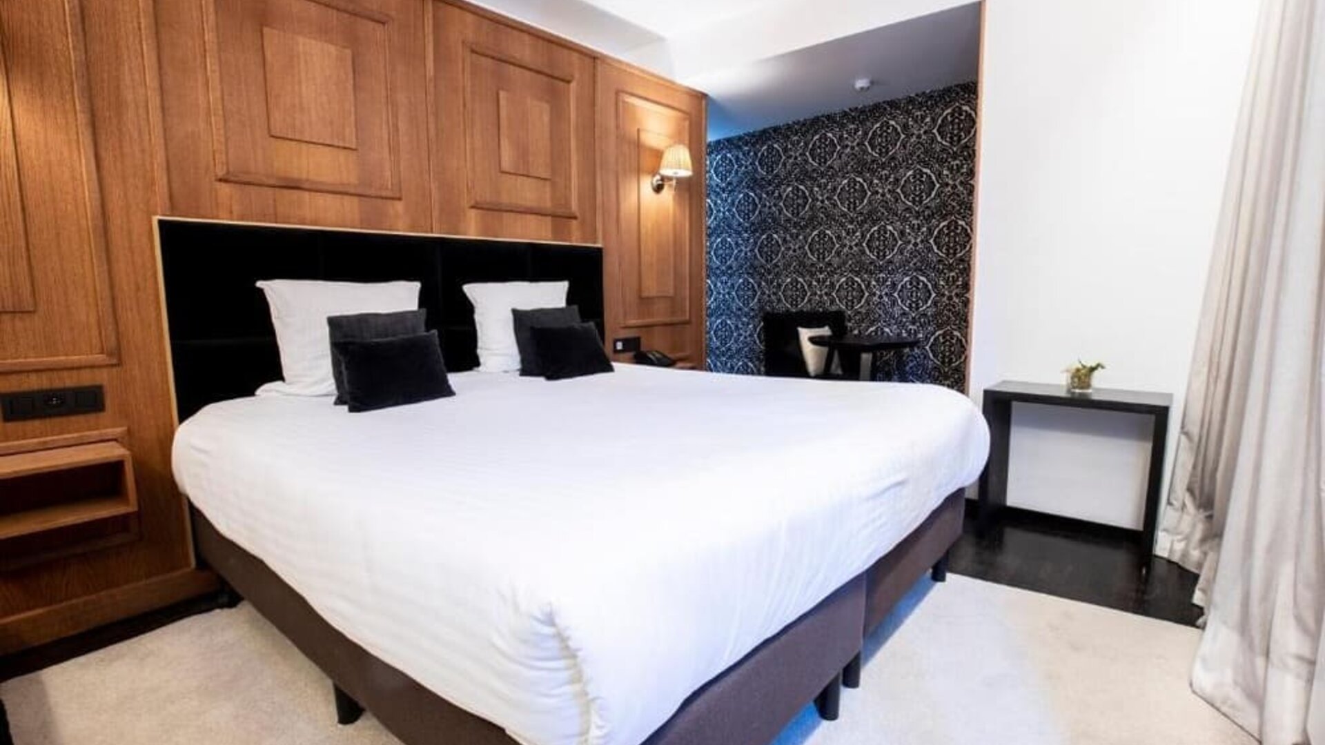 King bedroom with elegant wood finishes and seating nook at Hôtel Espérance.