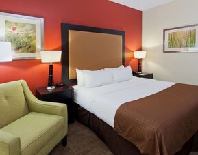 Guest room with king bed, lounge chair, and warm modern décor at Holiday Inn Downtown Shreveport.