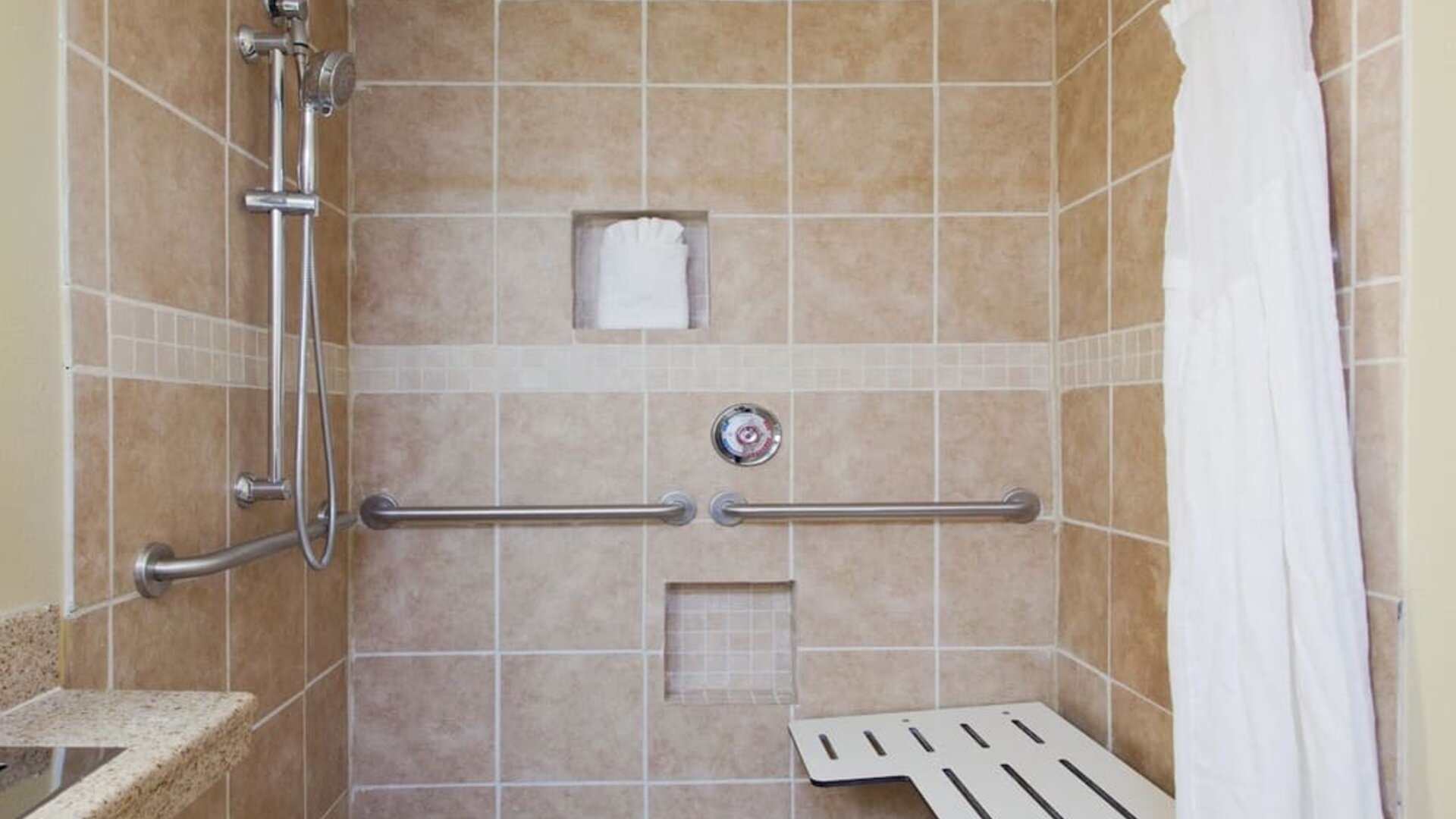 Accessible roll-in shower with grab bars and built-in seating at Holiday Inn Downtown Shreveport.