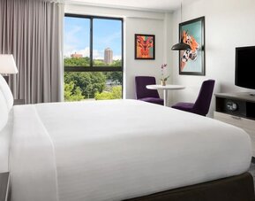 Modern king guest room with colorful artwork and park views at Hotel Studio Allston.