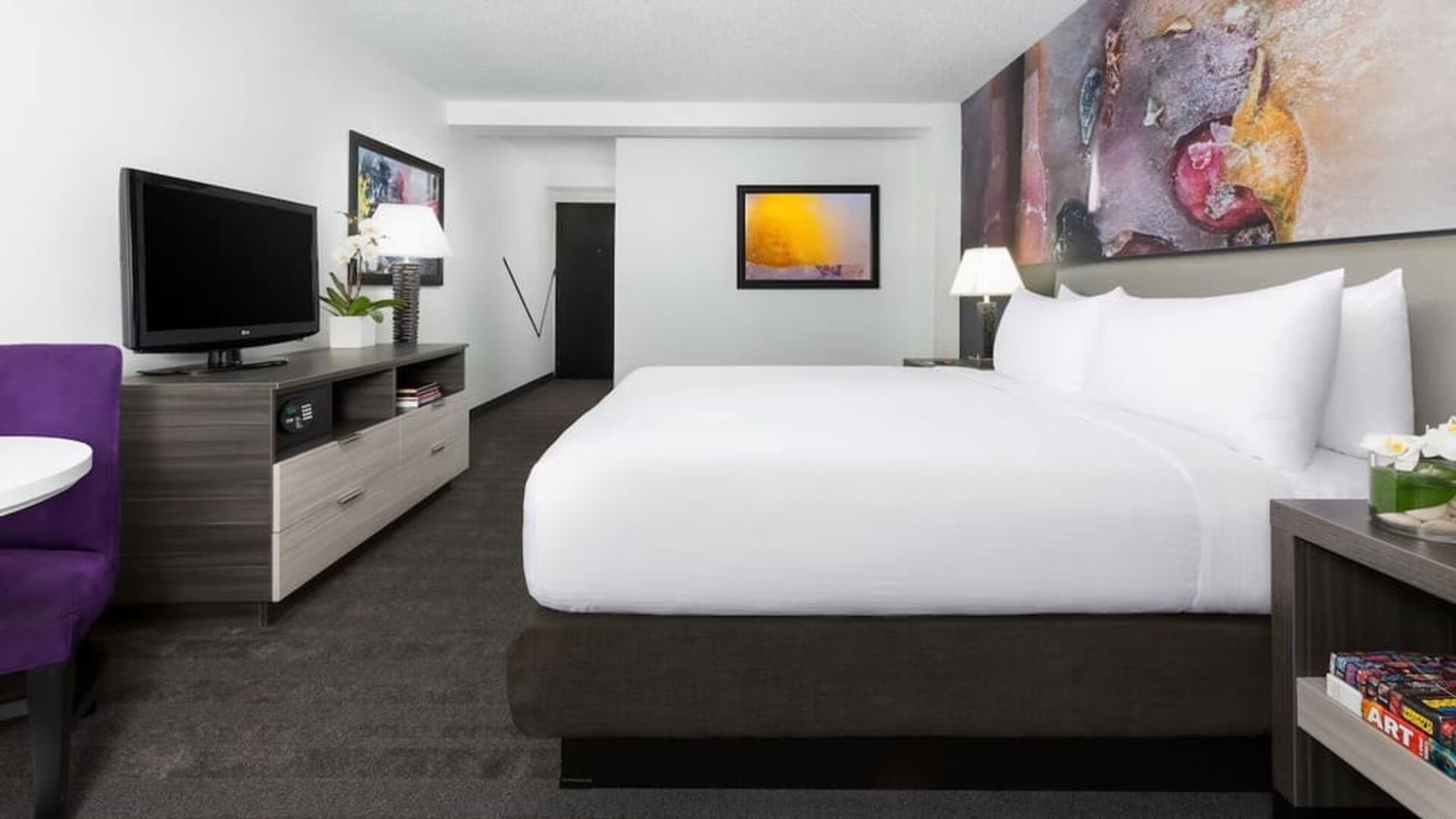 Spacious king guest room with modern furnishings and abstract artwork at Hotel Studio Allston.