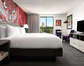 Contemporary guest room with large bed, modern décor, and scenic views at Hotel Studio Allston.
