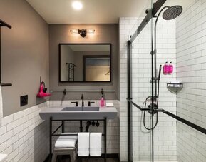 Compact bathroom with rainfall shower, subway tile walls, and floating vanity at Moxy Boston Downtown.
