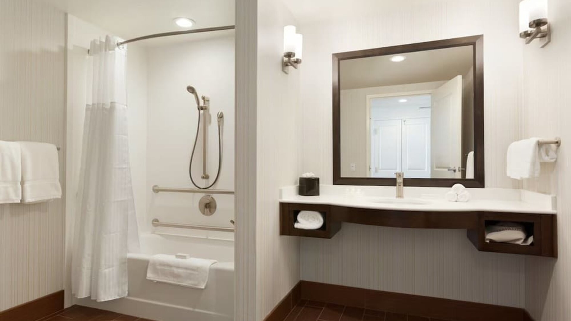 Accessible bathroom with grab bars, bathtub shower combo, and large vanity at Hilton Garden Inn Boston Logan Airport.