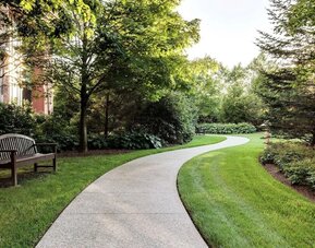 Curved garden walkway with benches, trees, and landscaped greenery at Hilton Boston Logan Airport.
